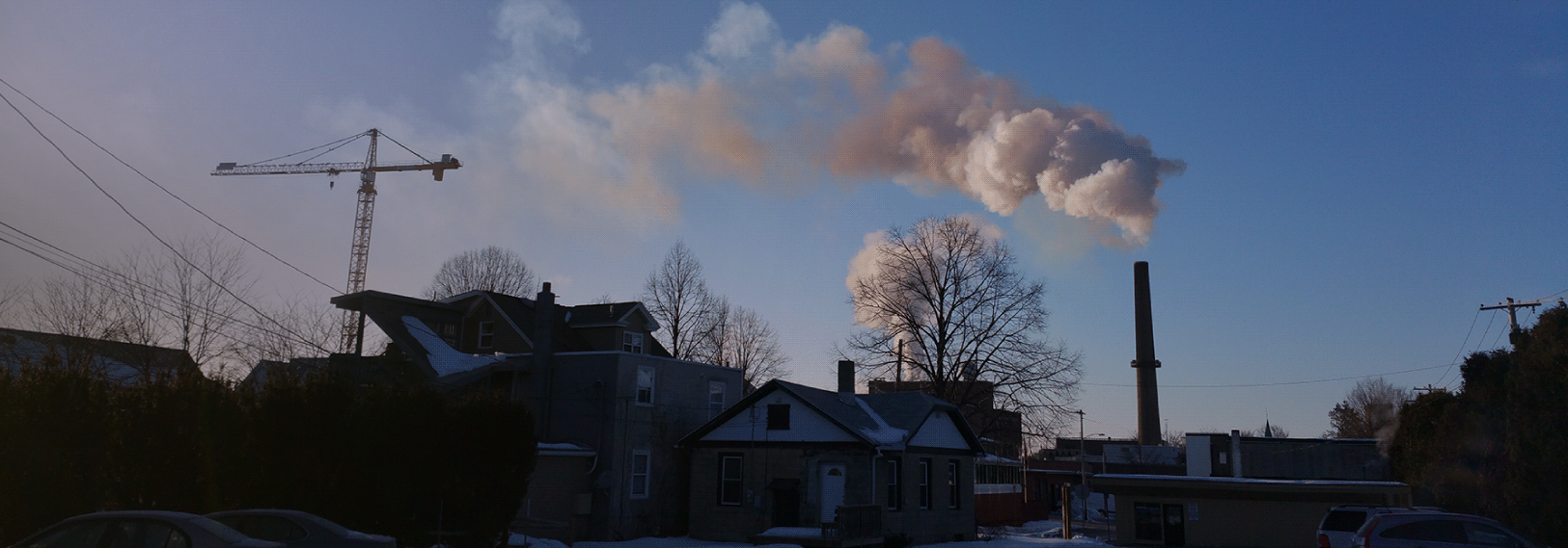 Smoke billows from a smokestack over a suburban neighborhood